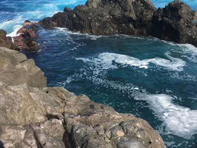 Una piscina natural volcánica turquesa en roca de lava negra junto al océano